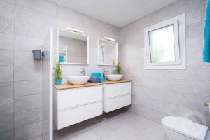 modernes Badezimmer mit ebenerdiger Dusche, zwei Waschbecken und einer Toilette