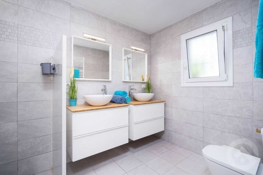 modernes Badezimmer mit ebenerdiger Dusche, zwei Waschbecken und einer Toilette
