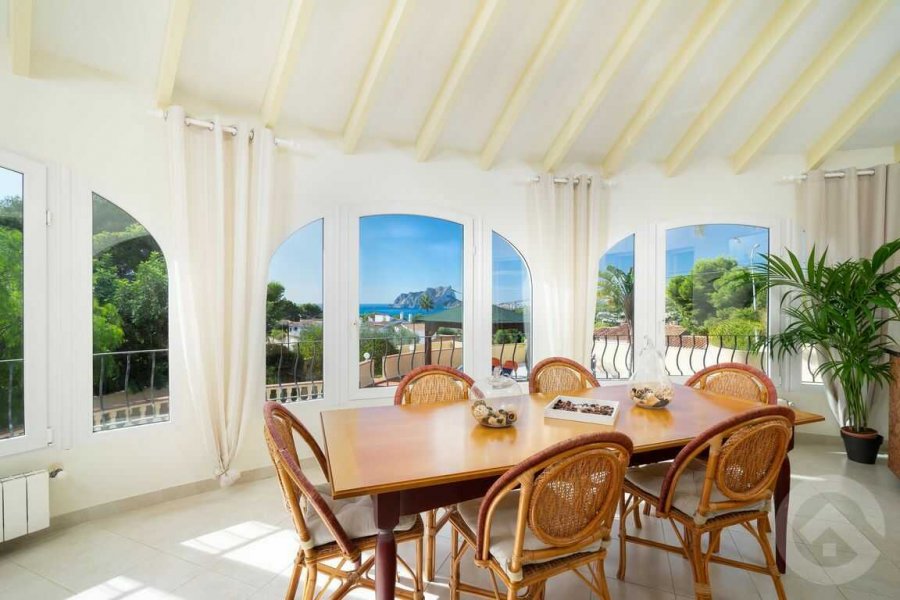 Wintergarten mit großem Esstisch und Panoramablick auf das Meer