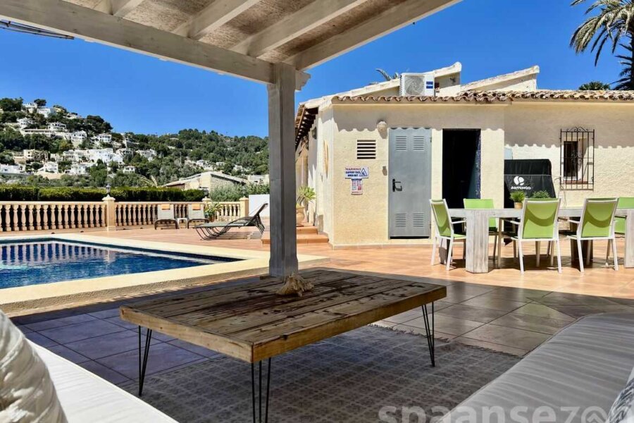 Überdachter Loungebereich mit Blick auf den Pool und die Berge von Moraira